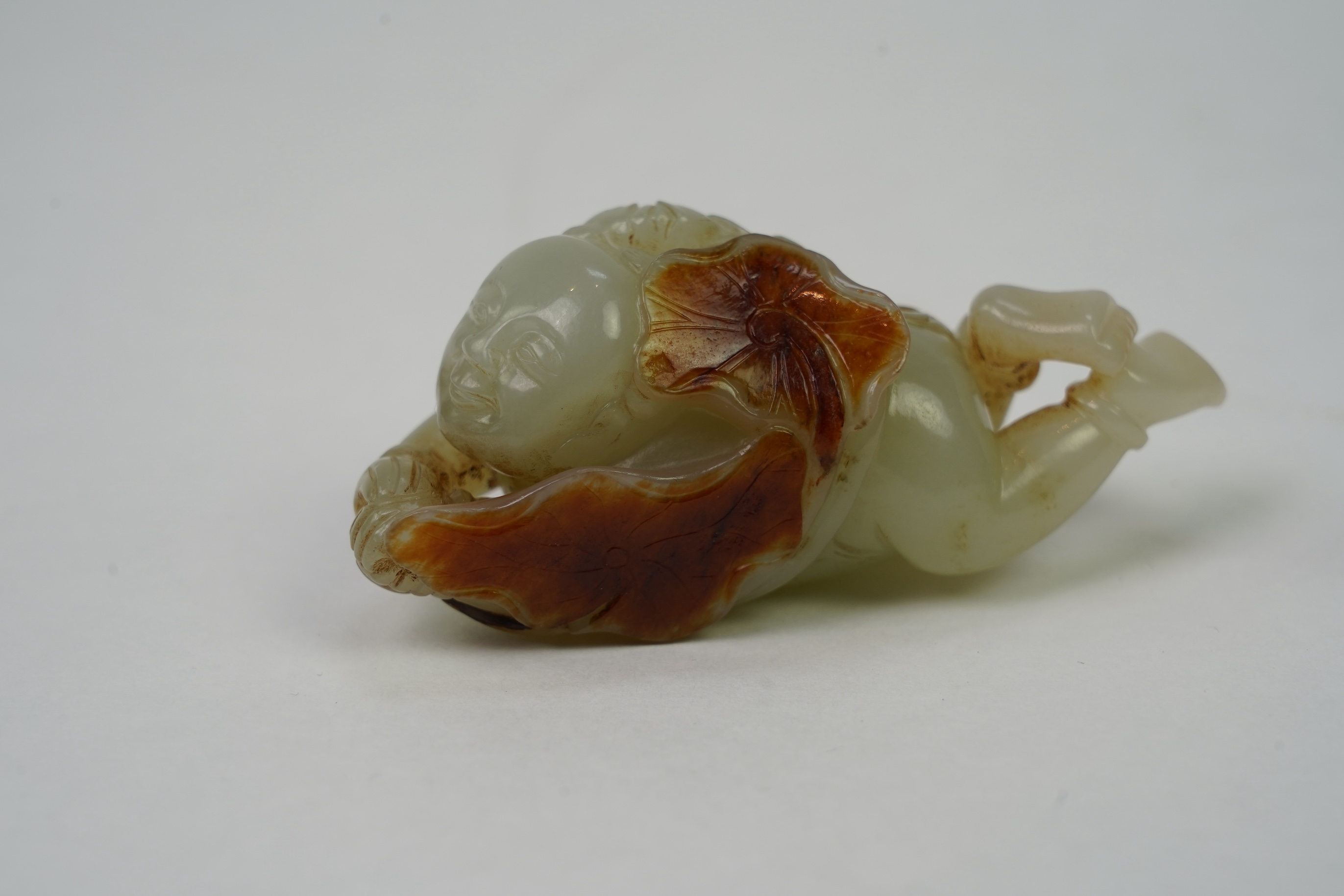 A Chinese pale celadon and russet skin jade figure of a boy and lotus